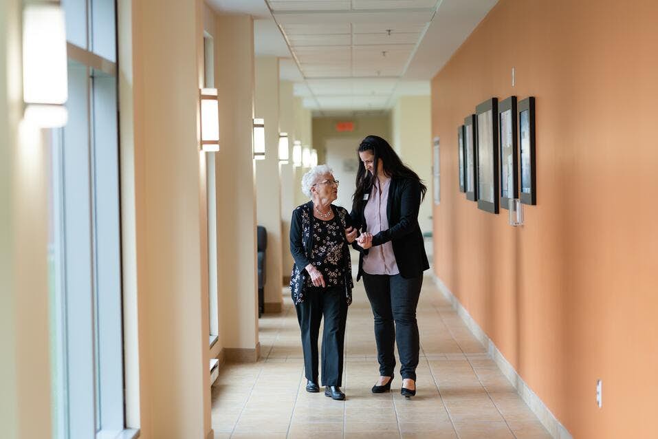 Chartwell care support staff helping a senior resident walk along the corridor